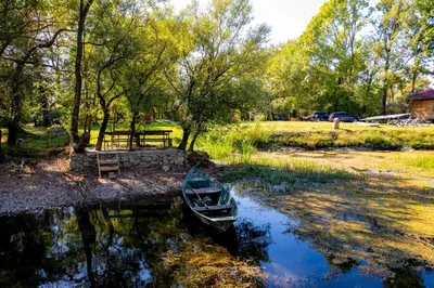 a small boat sitting in the water in a park at Camp River Skadar Lake in Gostilj