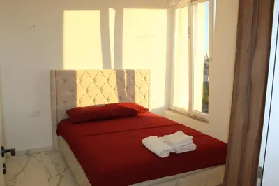a bedroom with a red bed with towels on it at Lunis Dobra Voda in Dobra Voda