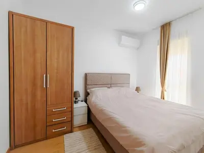 a bedroom with a large bed and a wooden cabinet at Modern City Apartment Budva3-Central Location,5 min to Beach in Kravlja