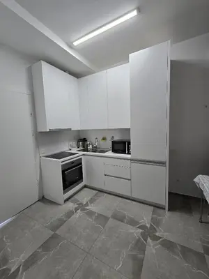 a kitchen with white cabinets and a tile floor at Апартаменты Дельмар in Becici