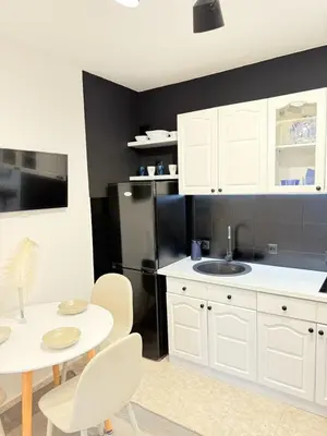 a kitchen with white cabinets and a table and a refrigerator at Aurora Apartment in Petrovac na Moru