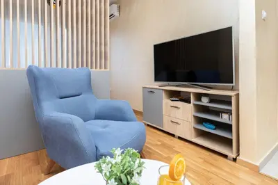 a living room with a blue chair and a television at Princess Milena Apartments - Apartment Milena in Becici