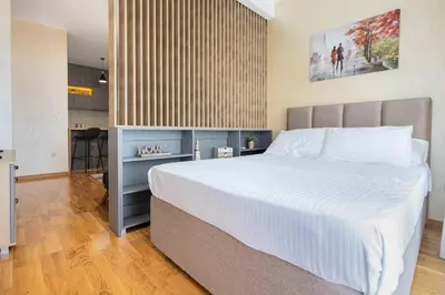 a bedroom with a large white bed and a kitchen at Princess Milena Apartments - Apartment Milena in Becici