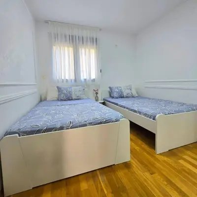 two beds in a room with white walls and wood floors at Apartment Nemanja by Princess Milena in Becici