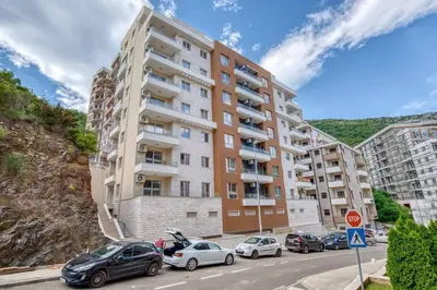 an apartment building with cars parked in a parking lot at Princess Milena Apartments - Studio Balsa in Becici