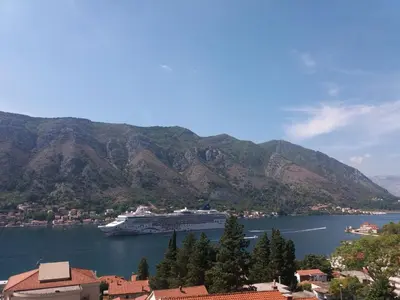 a cruise ship in a large body of water with mountains at Apartments Peranovic in Kotor