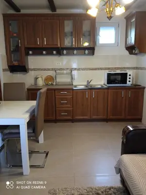 a kitchen with wooden cabinets and a table with a microwave at Apartments Peranovic in Kotor