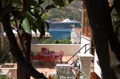 a patio with a table and chairs and a cruise ship at Apartments Peranovic in Kotor