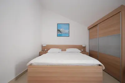 a bedroom with a large bed with a wooden headboard at Pansion Anita in Budva