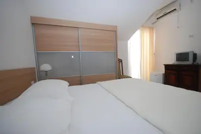 a bedroom with a white bed with a sliding glass door at Pansion Anita in Budva