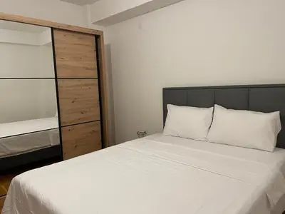 a bedroom with a large white bed and a closet at Viktorija Apartment Petrovac in Petrovac na Moru