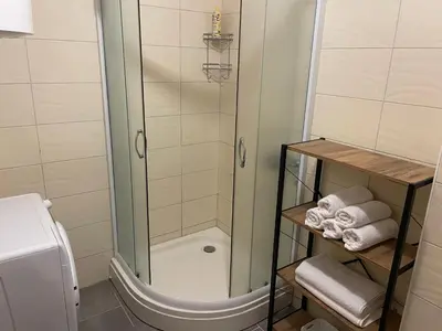 a shower in a bathroom with towels on a shelf at Viktorija Apartment Petrovac in Petrovac na Moru