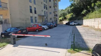 a parking lot with cars parked next to a building at Viktorija Apartment Petrovac in Petrovac na Moru