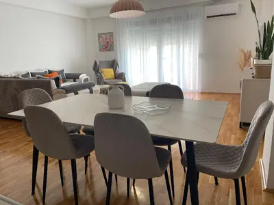 a living room with a dining room table and chairs at Viktorija Apartment Petrovac in Petrovac na Moru