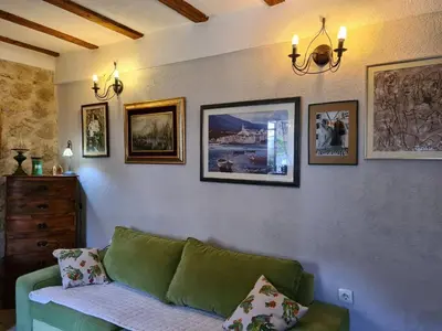 a living room with a green couch and pictures on the wall at Charming 3 Bedroom House in Skaljari Montenegro with Garden View in Škaljari