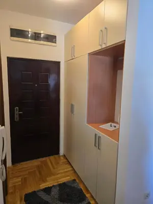 a small kitchen with a black door and white cabinets at Apartment tuski put in Podgorica