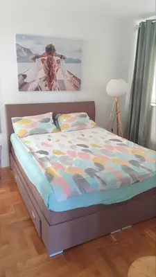a bed in a bedroom with a painting on the wall at Bojana PLUS - Sea View in Petrovac na Moru