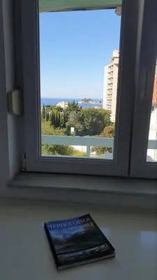 a book sitting on a table next to a window at Bojana PLUS - Sea View in Petrovac na Moru