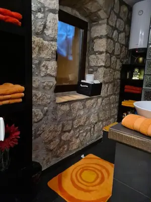 a bathroom with a stone wall and a mirror at Cheerful three bedroms house with free parking in Kotor