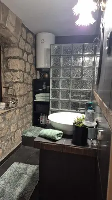 a bathroom with a sink and a stone wall at Cheerful three bedroms house with free parking in Kotor