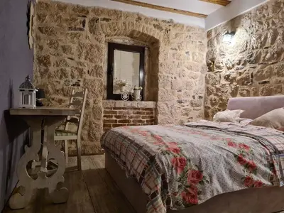 a bedroom with stone walls and a bed and a table at Cheerful three bedroms house with free parking in Kotor