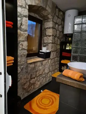 a bathroom with a sink and a stone wall at Cheerful three bedroms house with free parking in Kotor