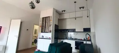 a kitchen with white cabinets and a green couch at Harmony in Bar