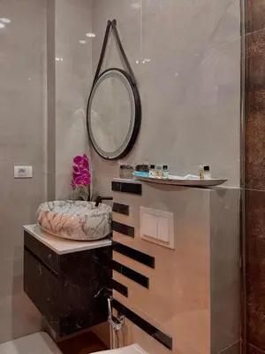 a bathroom with a round mirror and a sink at Apartman Bulevar in Ulcinj