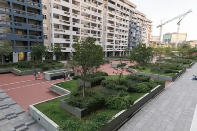 a park with trees and bushes in front of a building at A&T Lux in Podgorica
