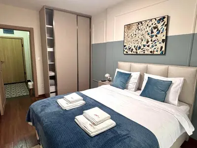 a bedroom with a large bed with towels on it at A&T Lux in Podgorica