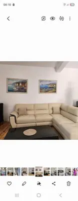 a living room with a white couch and paintings on the wall at Ana in Becici