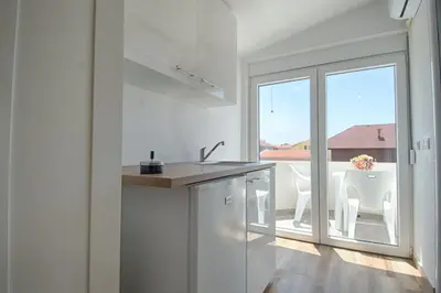 a white kitchen with a view of a balcony at Biševo Apartmani in Donji Štoj