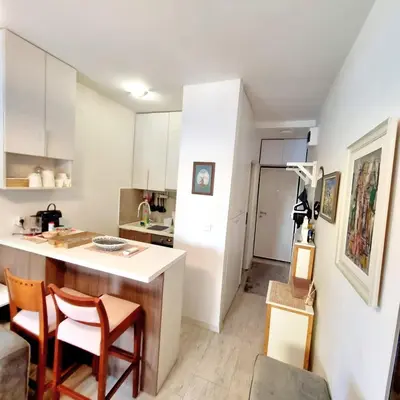 a kitchen with white cabinets and a counter and chairs at Manjastan in Podgorica
