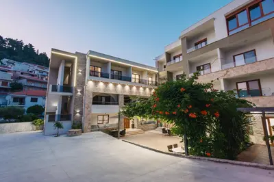 an apartment building with a courtyard with red flowers at APART-HOTEL PRESiDENT 2 in Ulcinj