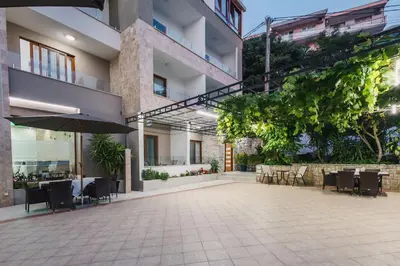 an outdoor patio with tables and chairs and an umbrella at APART-HOTEL PRESiDENT 2 in Ulcinj
