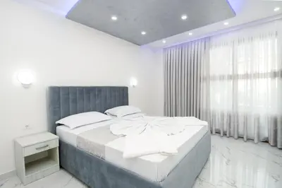 a white bedroom with a large bed and a window at APART-HOTEL PRESiDENT 2 in Ulcinj