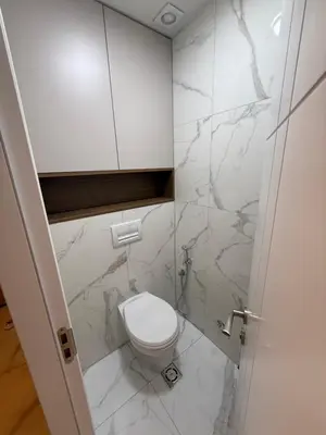 a bathroom with a white toilet and marble walls at Diamond H in Podgorica