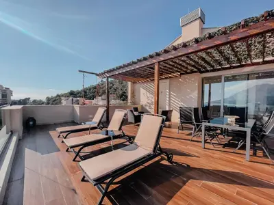 a deck with chairs and tables on a roof at Luxury Horizon Penthouse Budva in Becici