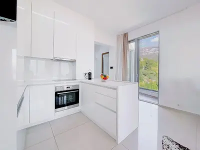 a white kitchen with white cabinets and a window at Luxury Horizon Penthouse Budva in Becici