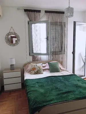 a bedroom with a bed with green sheets and a window at Ardea apart in Budva
