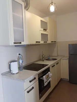 a kitchen with white cabinets and a sink and a refrigerator at Ardea apart in Budva