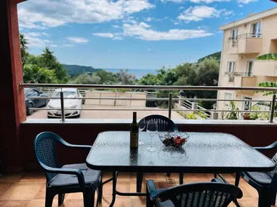 a table with a bottle of wine and chairs on a balcony at Apartman u Bečićima in Budva