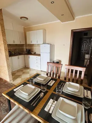 a kitchen with a wooden table with plates and glasses at Apartman u Bečićima in Budva