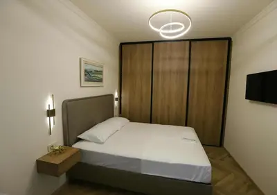 a bedroom with a bed with a wooden headboard at Stay Point Jerry - Podgorica City Apartment in Podgorica