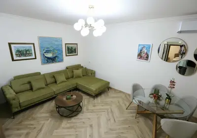 a living room with a green couch and a table at Stay Point Jerry - Podgorica City Apartment in Podgorica