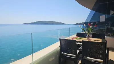 a balcony with a table with a view of the water at Azure Coast Residence Rafailovici -Seaside Living Apartments in Becici