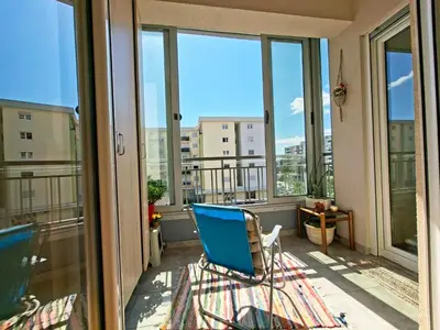 a room with a blue chair on a balcony with windows at The Lilac Lounge in Podgorica