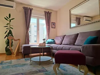 a living room with a purple couch and a mirror at The Lilac Lounge in Podgorica