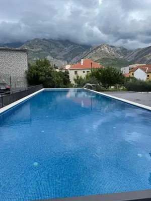 a large blue swimming pool with mountains in the background at Apartman Celuga in Bar