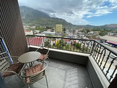 a balcony with a table and chairs and a view of a city at Apartman Celuga in Bar